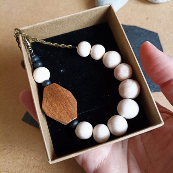Bracelet en perles nacrées blanches, rondes et perle en bois, petites perles noires.