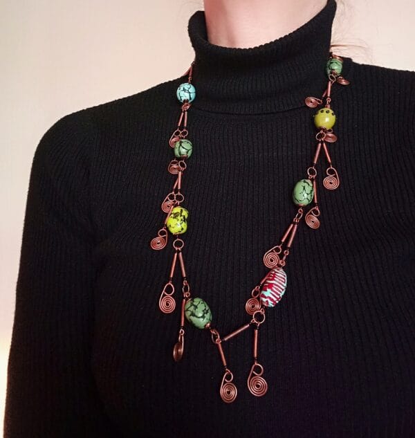 Collier long style bohème chic, perles vertes, éléments décoratifs en cuivre.