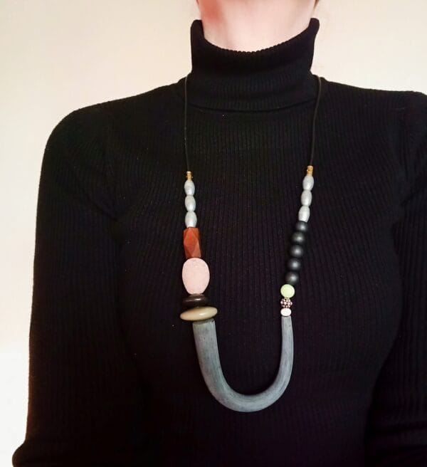 Collier long en perles noires, argentées et marron.