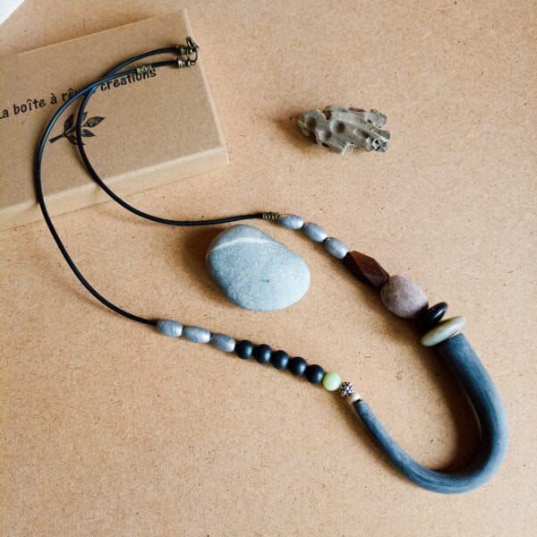 Collier long en perles noires, argentées et marron.