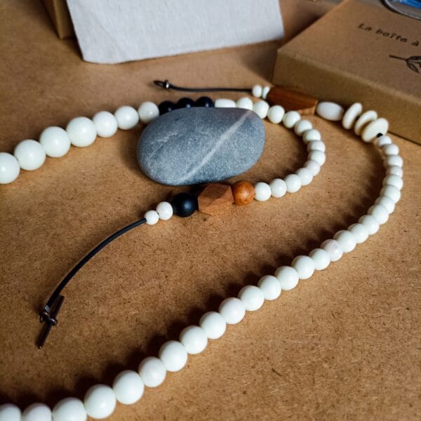 Collier long en perles blanches, bois et noires.