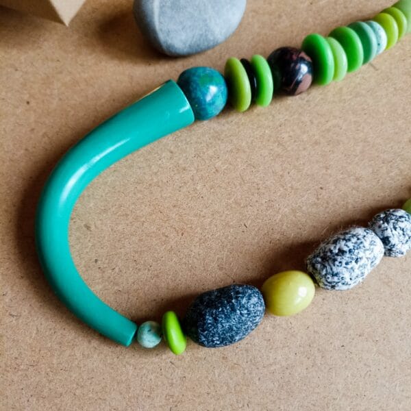 Collier mi-long en perles vertes plates, rondes, perles grises et blanches aspect pierre brute.