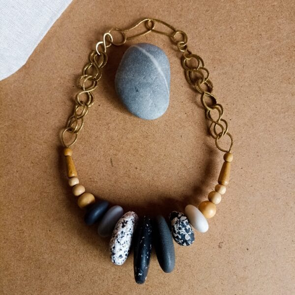 Collier court avec des perles noires, grises et blanches imitant les pierres. Perles en bois et en métal. Pièce unique faite main.