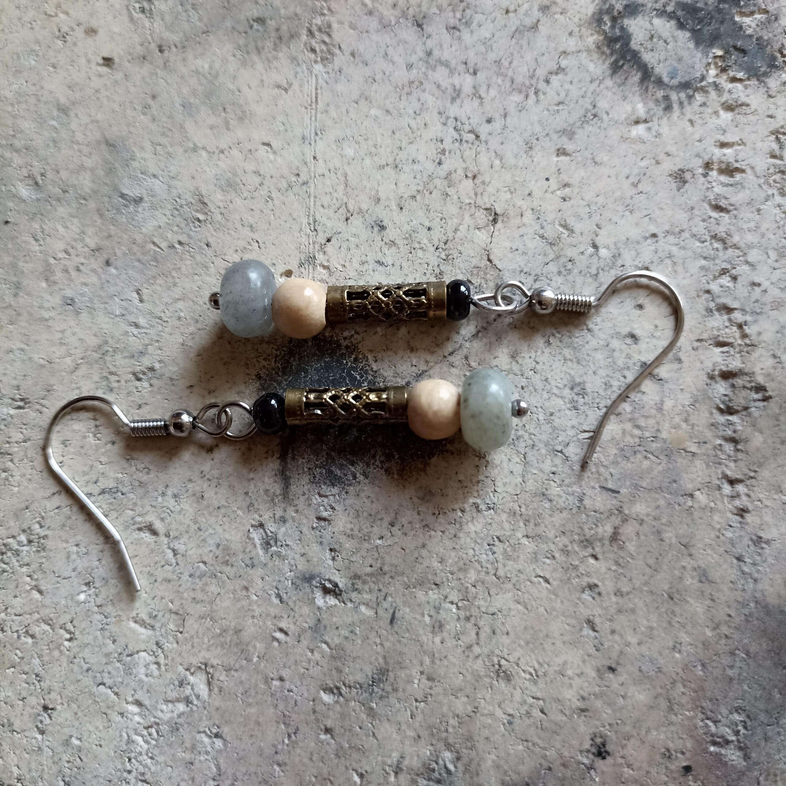 deux boucles d'oreilles posées sur un fond en béton