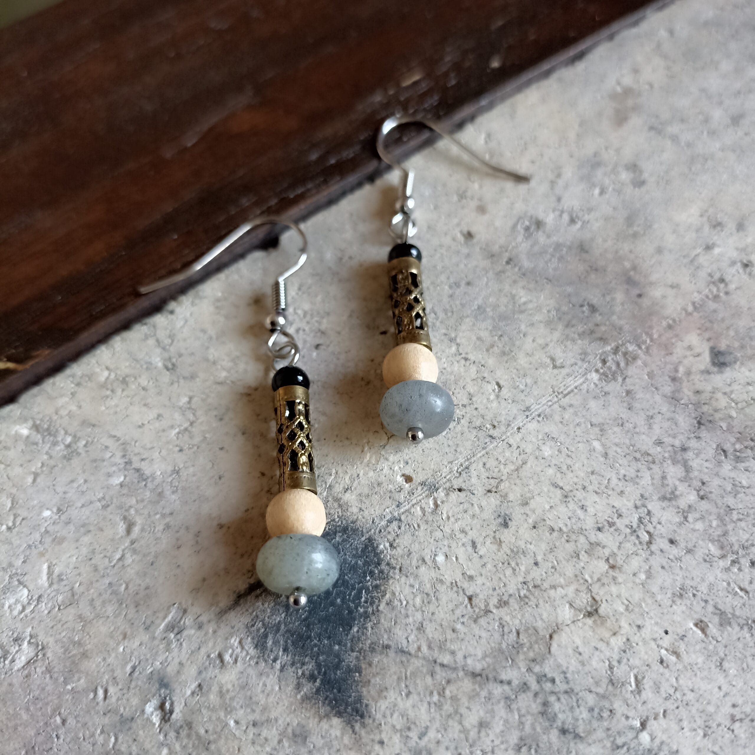 Boucles d'oreilles Labradora vues en gros plan sur un fond en béton.