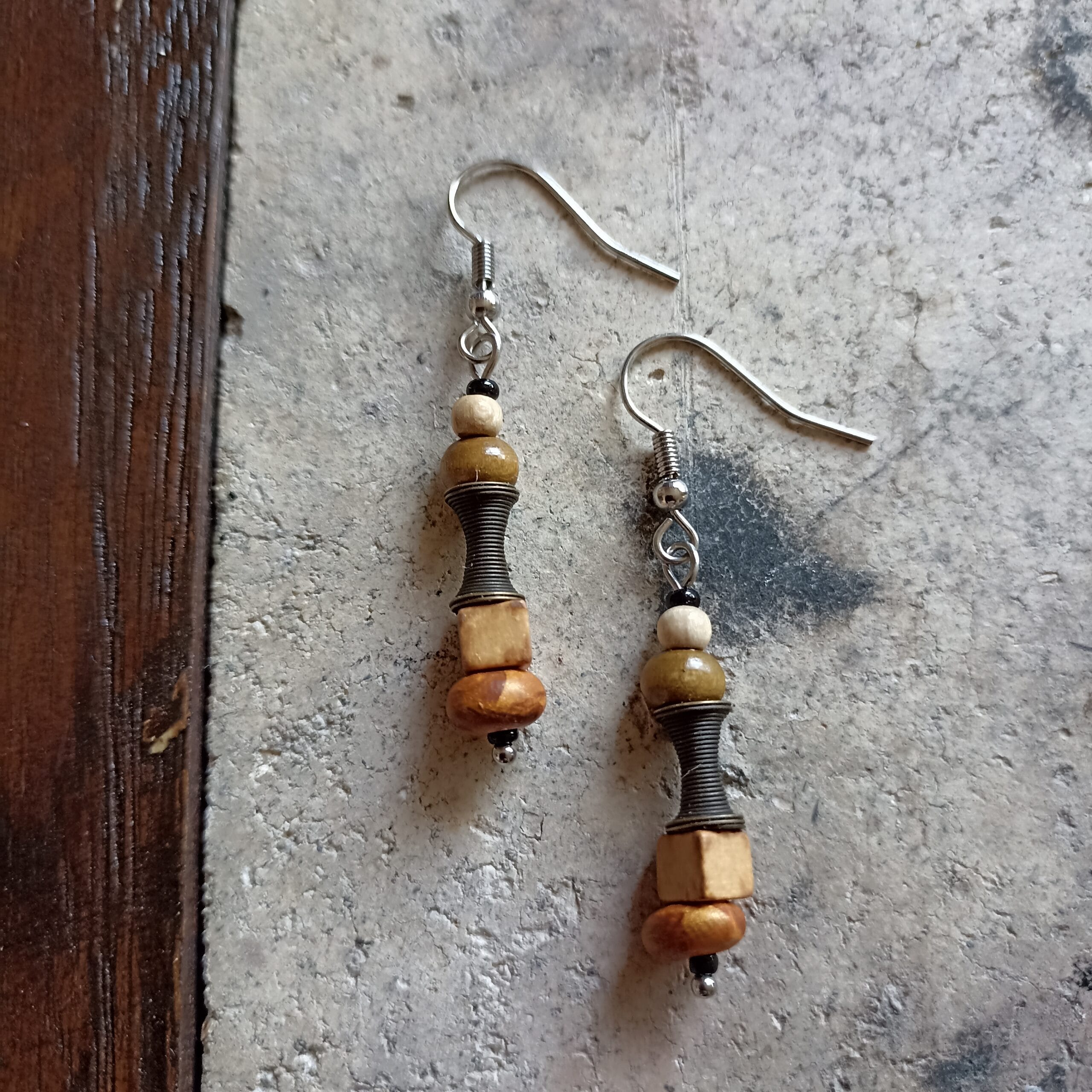 deux boucles d'oreilles posées sur un sol en béton