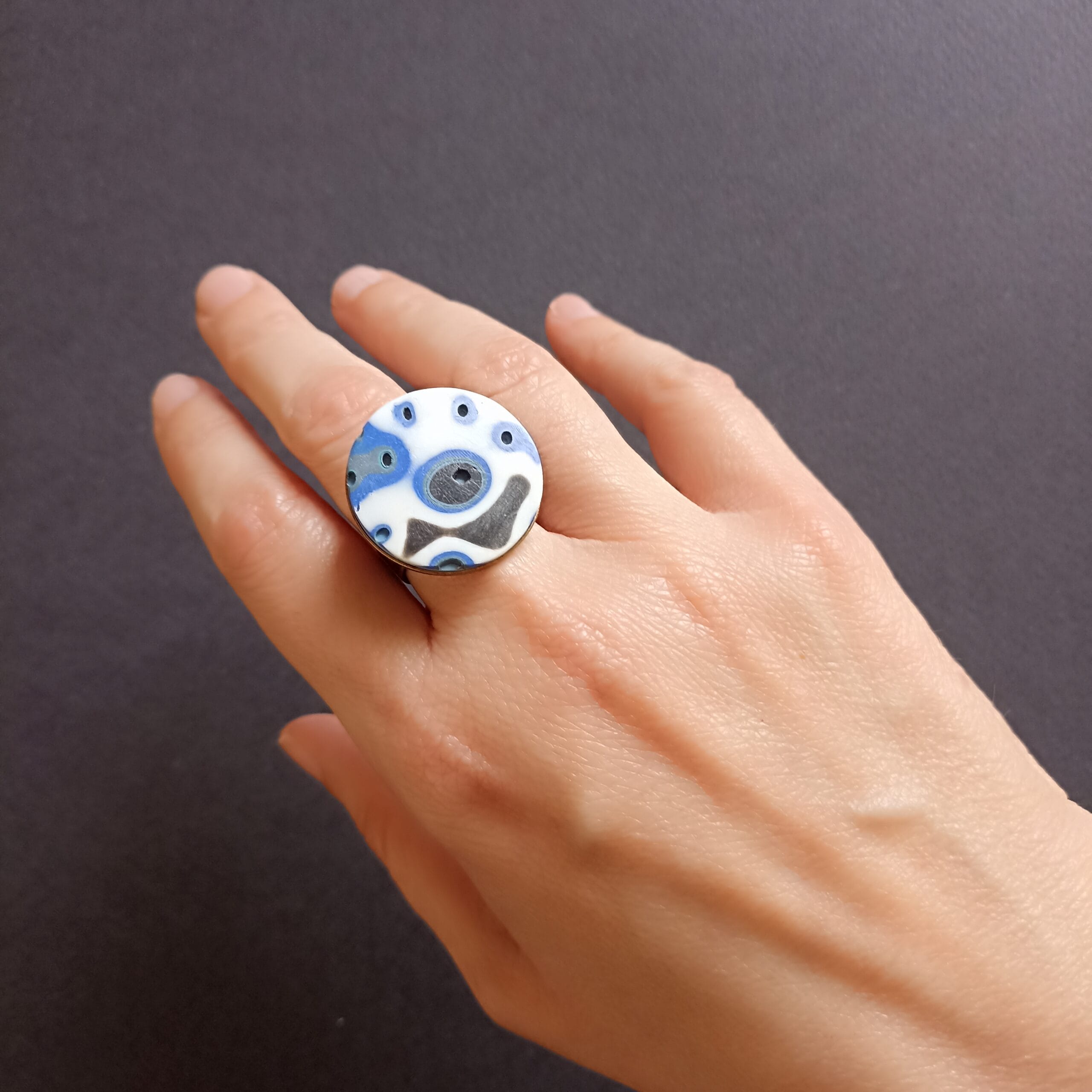 bague plateau ronde, blanche et bleue, portée sur un doigt