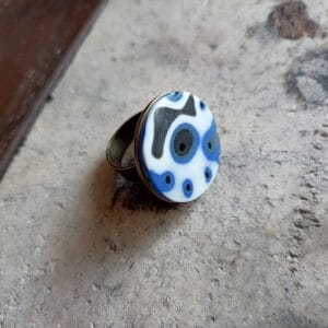 bague ronde, aux motifs bleus et blancs, posée sur un support en béton