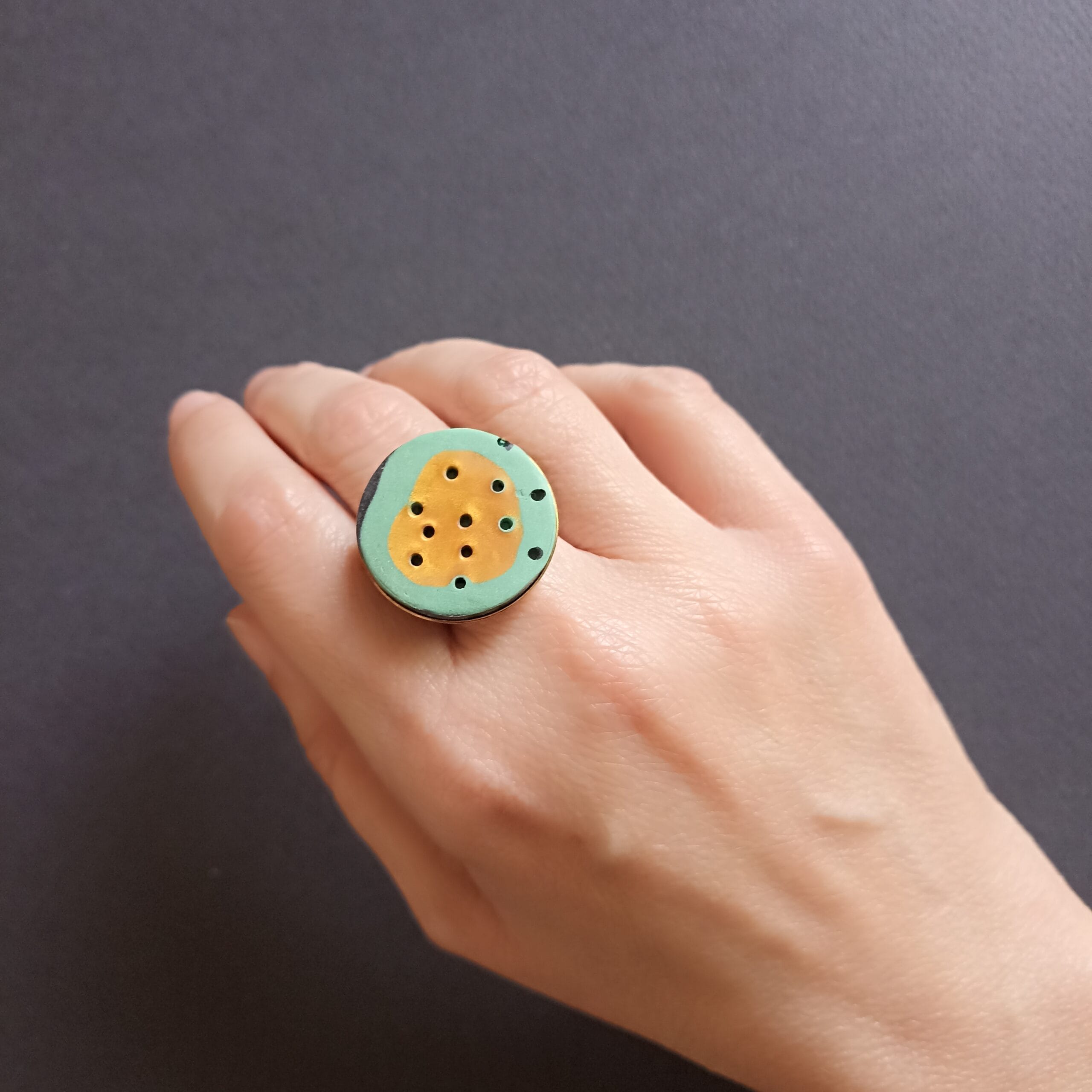 bague en pâte polymère verte et or, portée sur un doigt