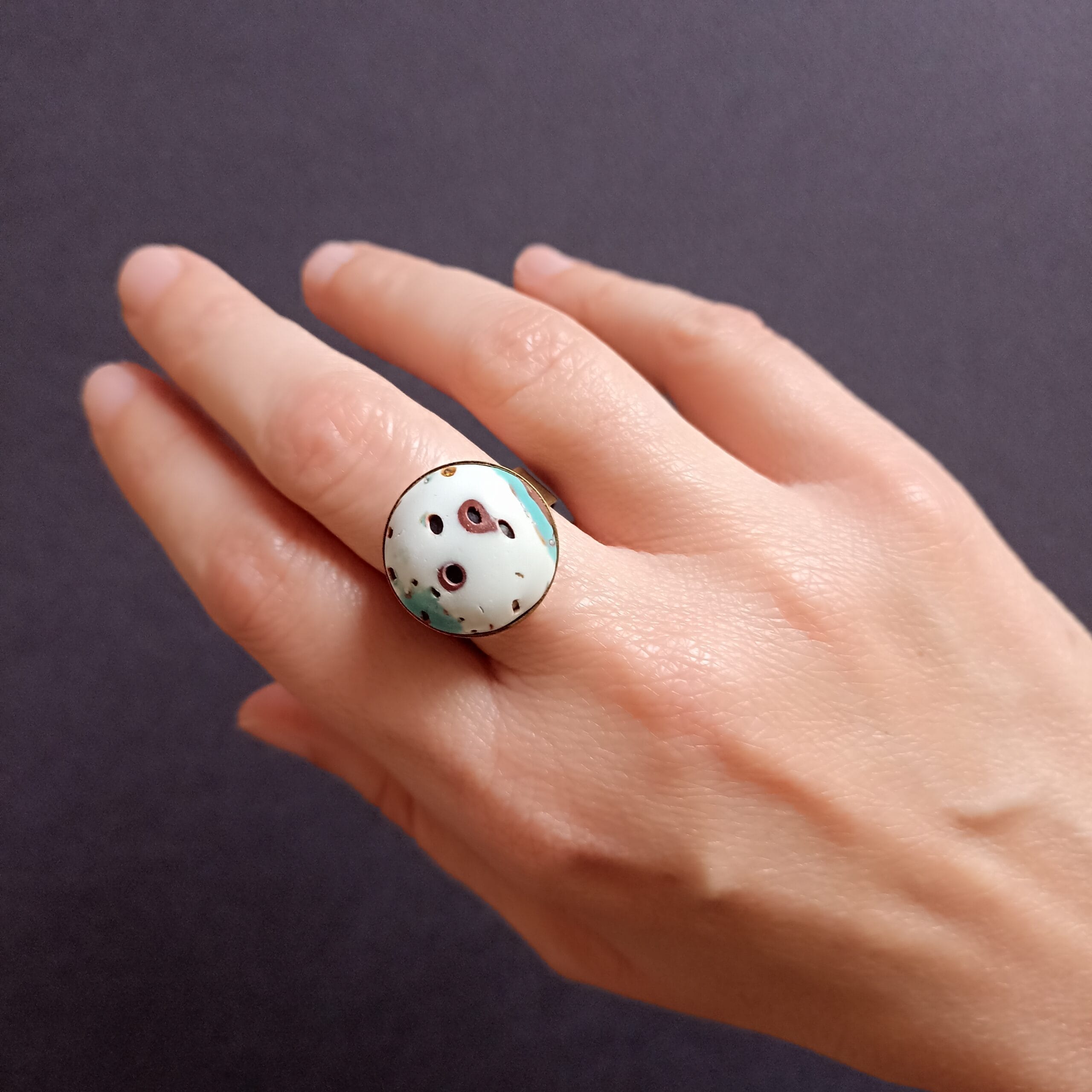 bague ronde en pâte polymère, portée sur une main.