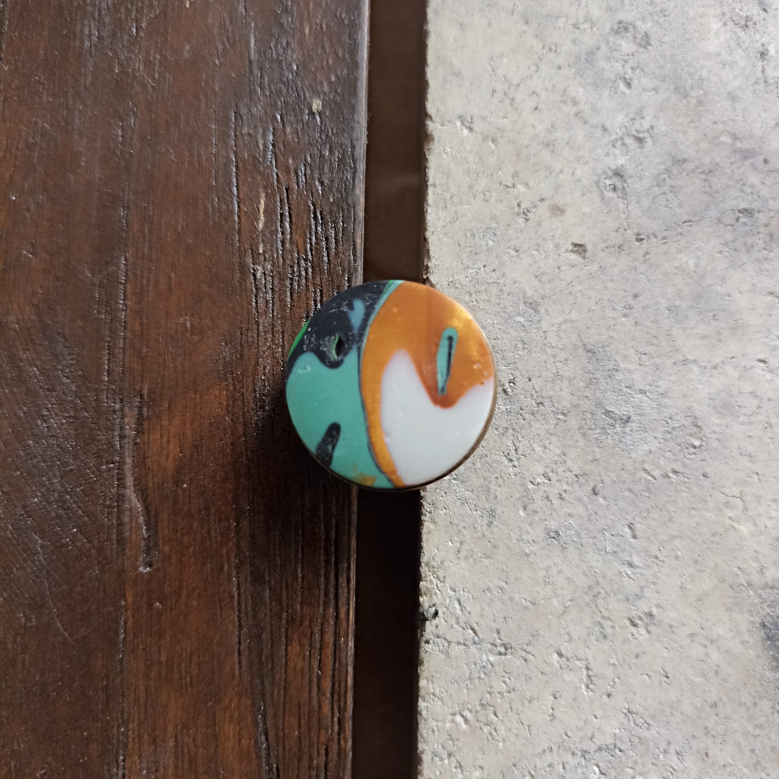 bague ronde verte et or vue du dessus, posée sur un fond en bois et béton