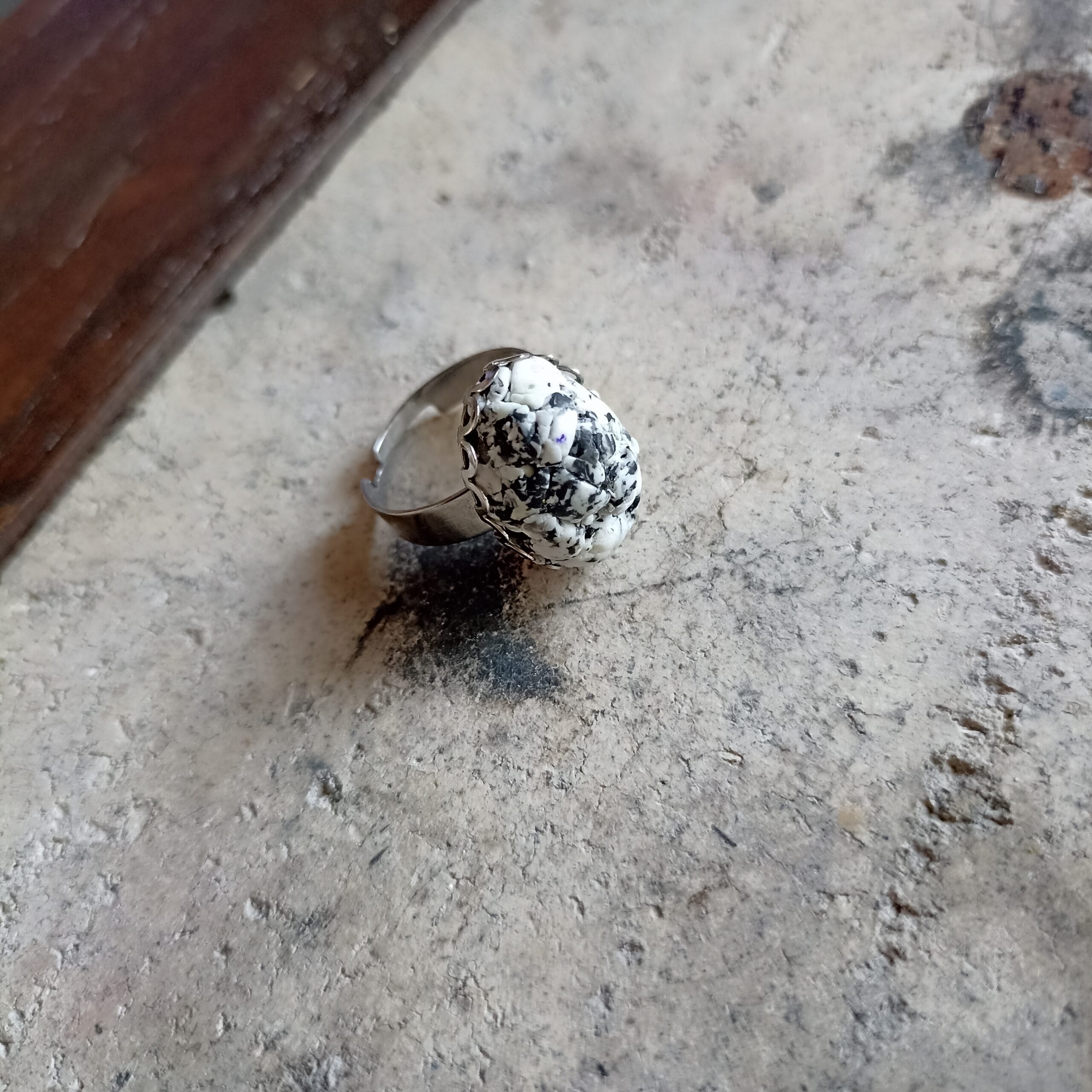 Bague en pâte polymère inspiration granite posée sur un fond gris .