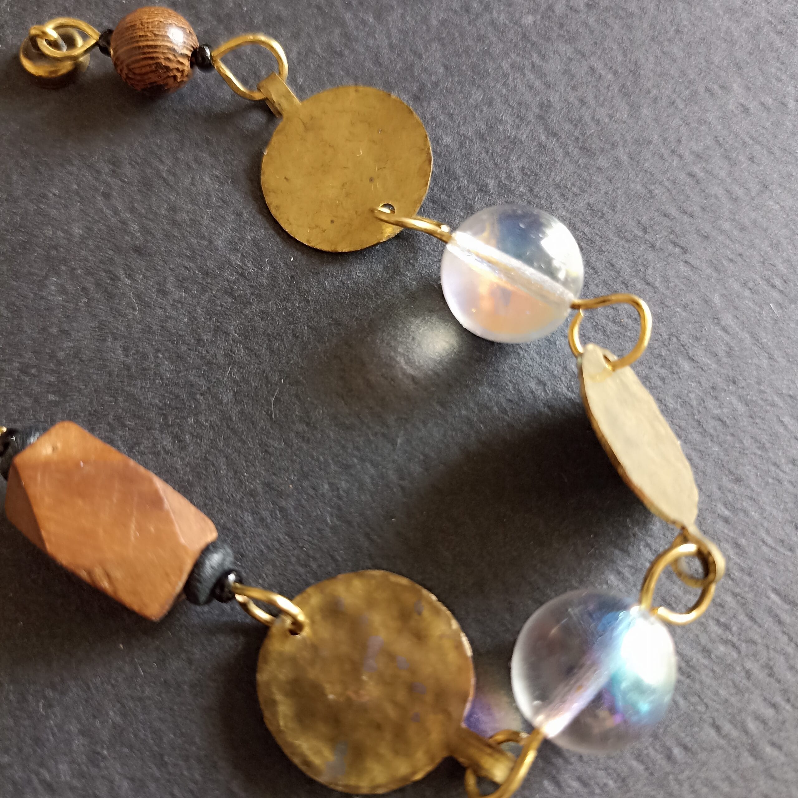 Gros plan sur les deux perles irisées du bracelet Goutte sur fond noir.