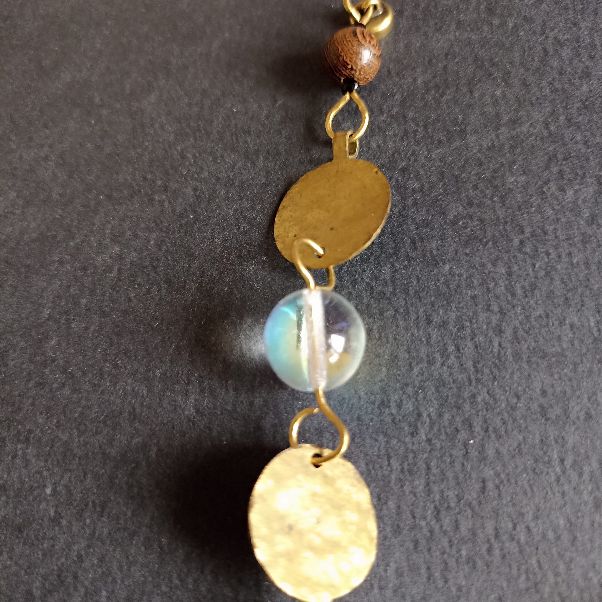 Détail d'une perle irisée et d'un élément en laiton du bracelet Goutte.