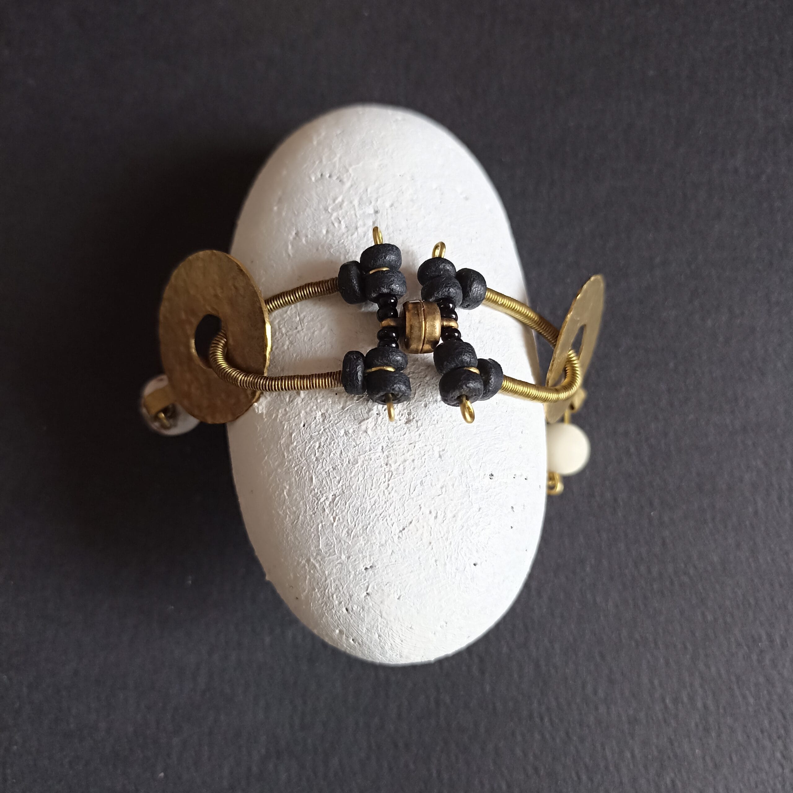 Bracelet Onde présenté enroulé sur un galet blanc.