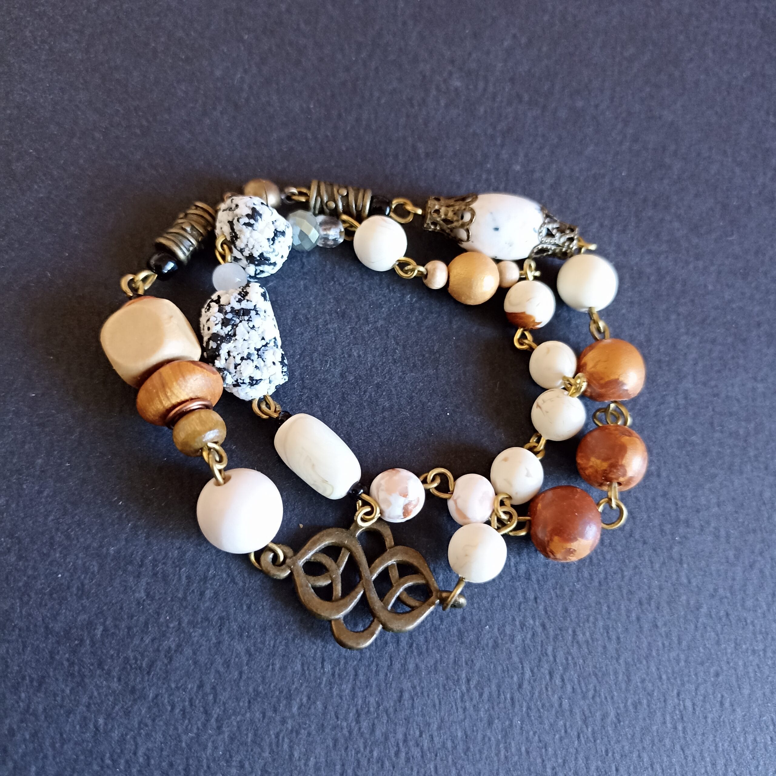 Bracelet aux couleurs naturelles avec un motif entrelacs celtique, posé sur un fond noir.