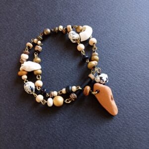 bracelet aux couleurs naturelles rappelant la plage, posé sur un fond noir.