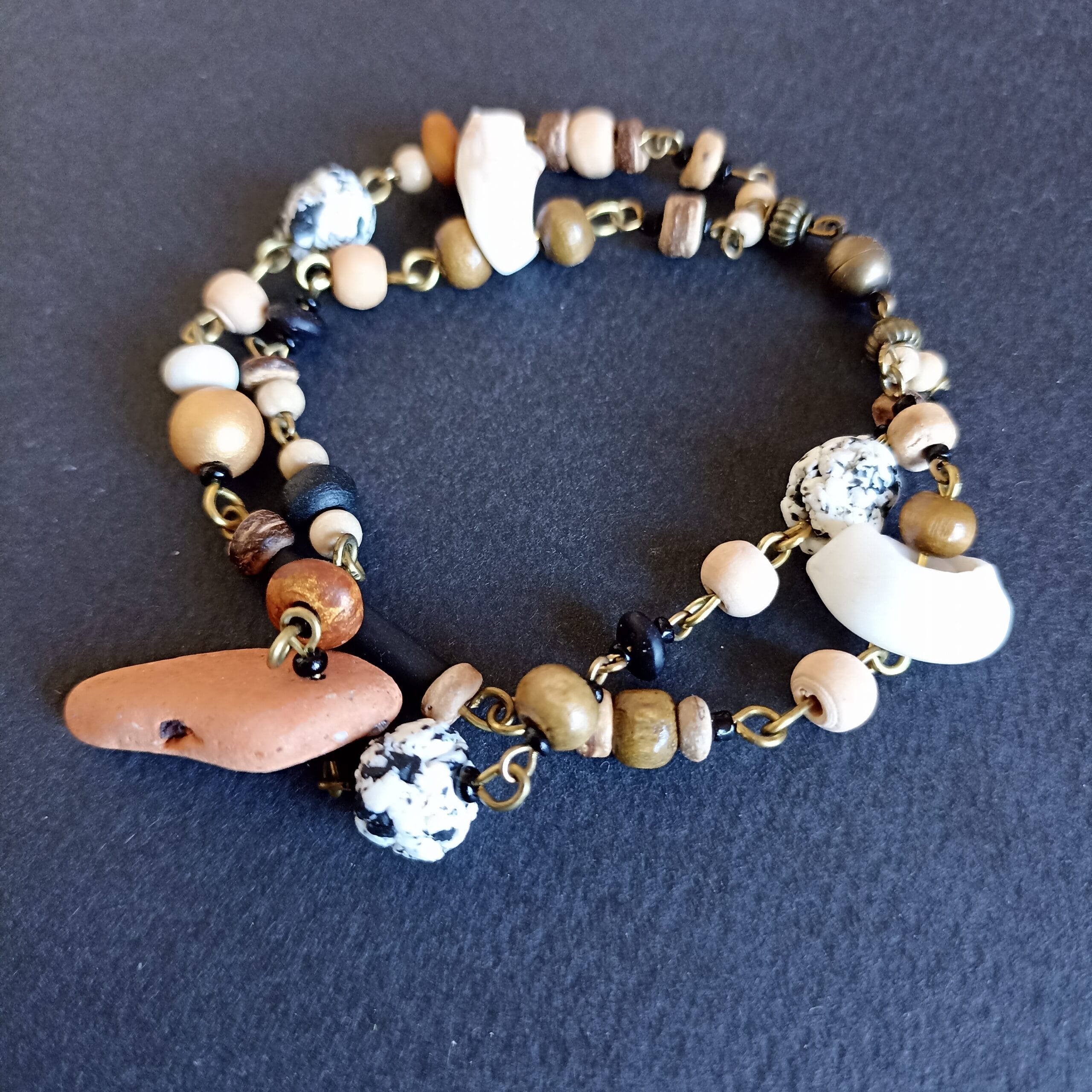 bracelet en coquillages et terre cuite, aux couleurs naturelles, sur son fond noir.