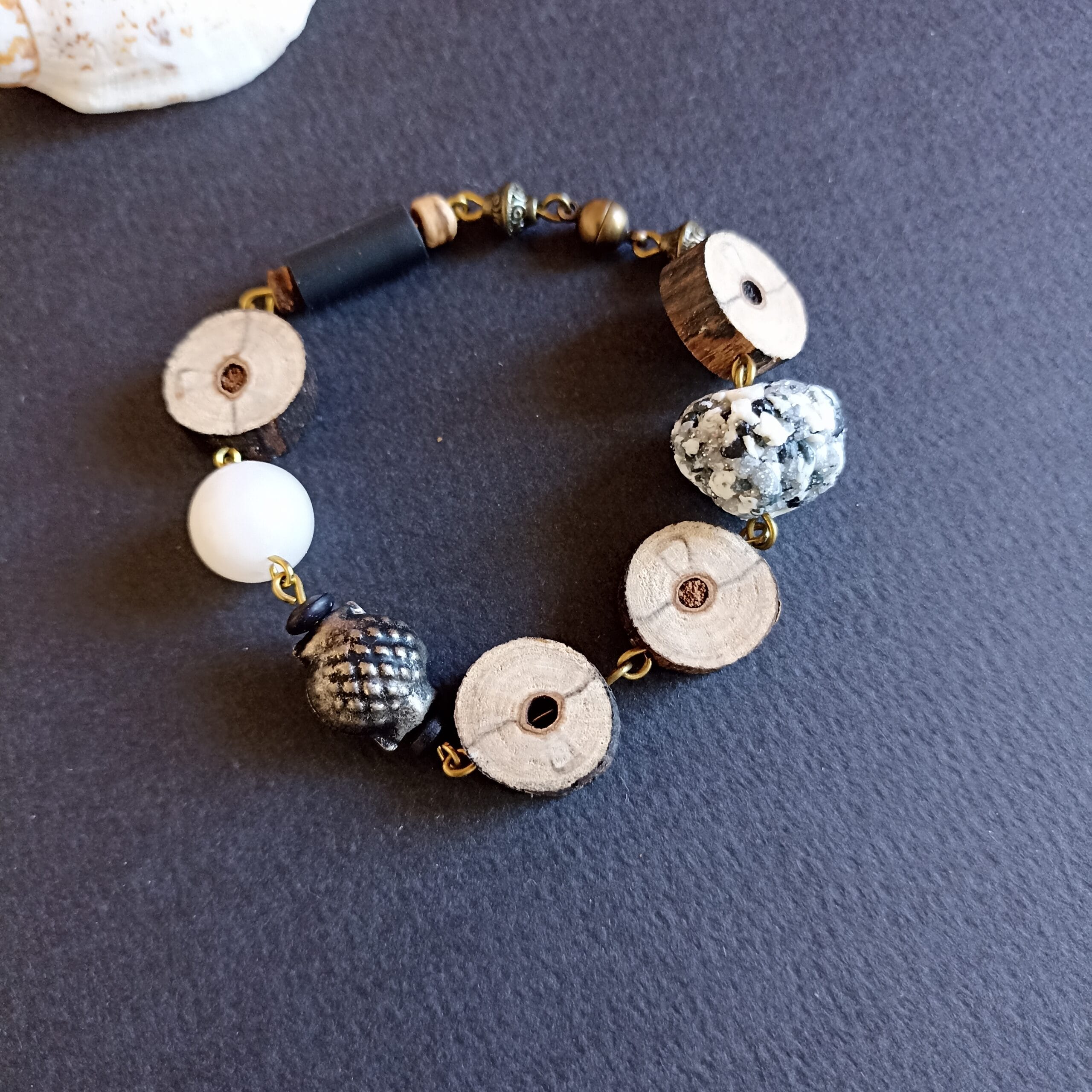 bracelet en rondelles de bois flotté et perles en pâte polymère, posé sur un fond noir.