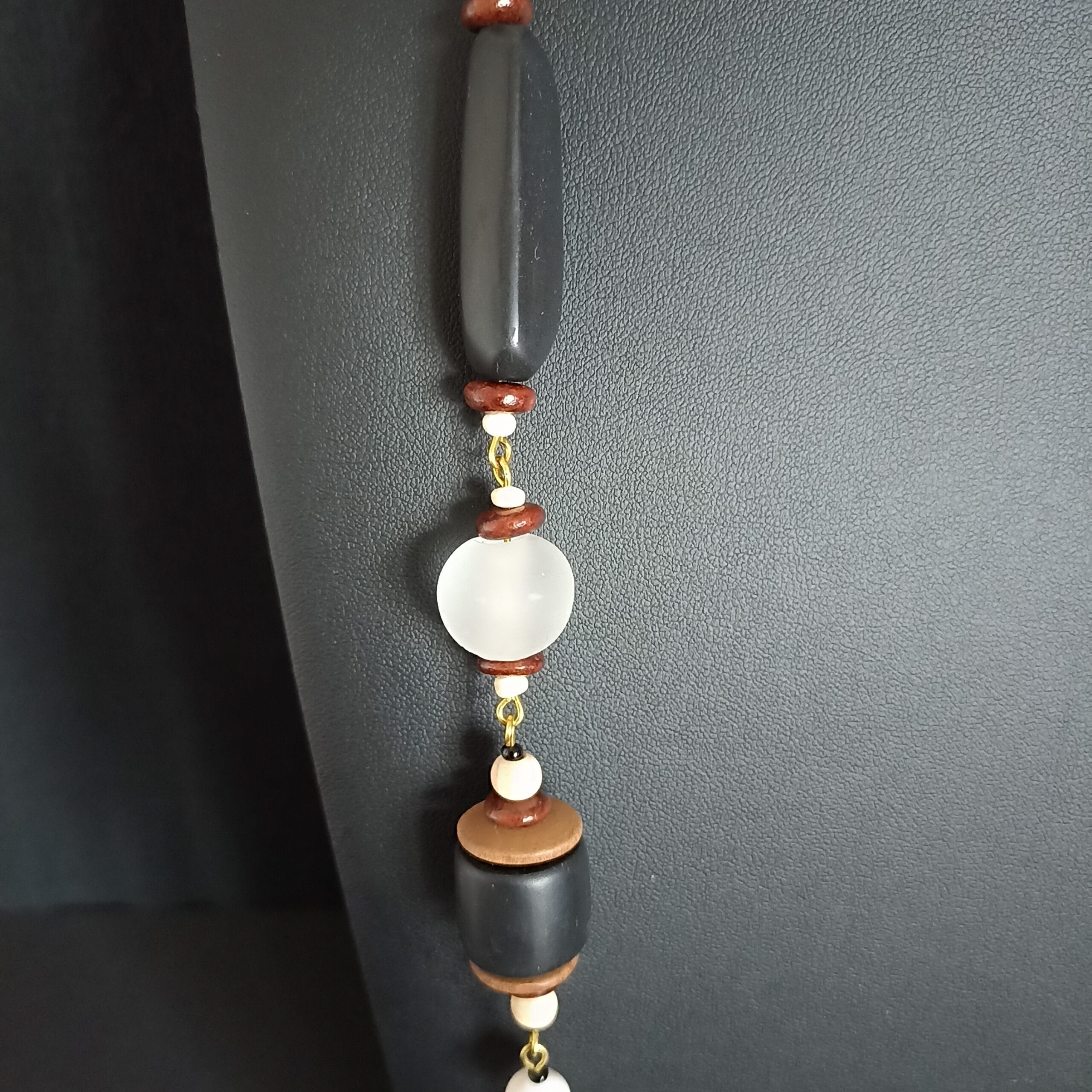 Détail du collier Thétis sur une perle noire longue et une perle blanche ronde en verre.