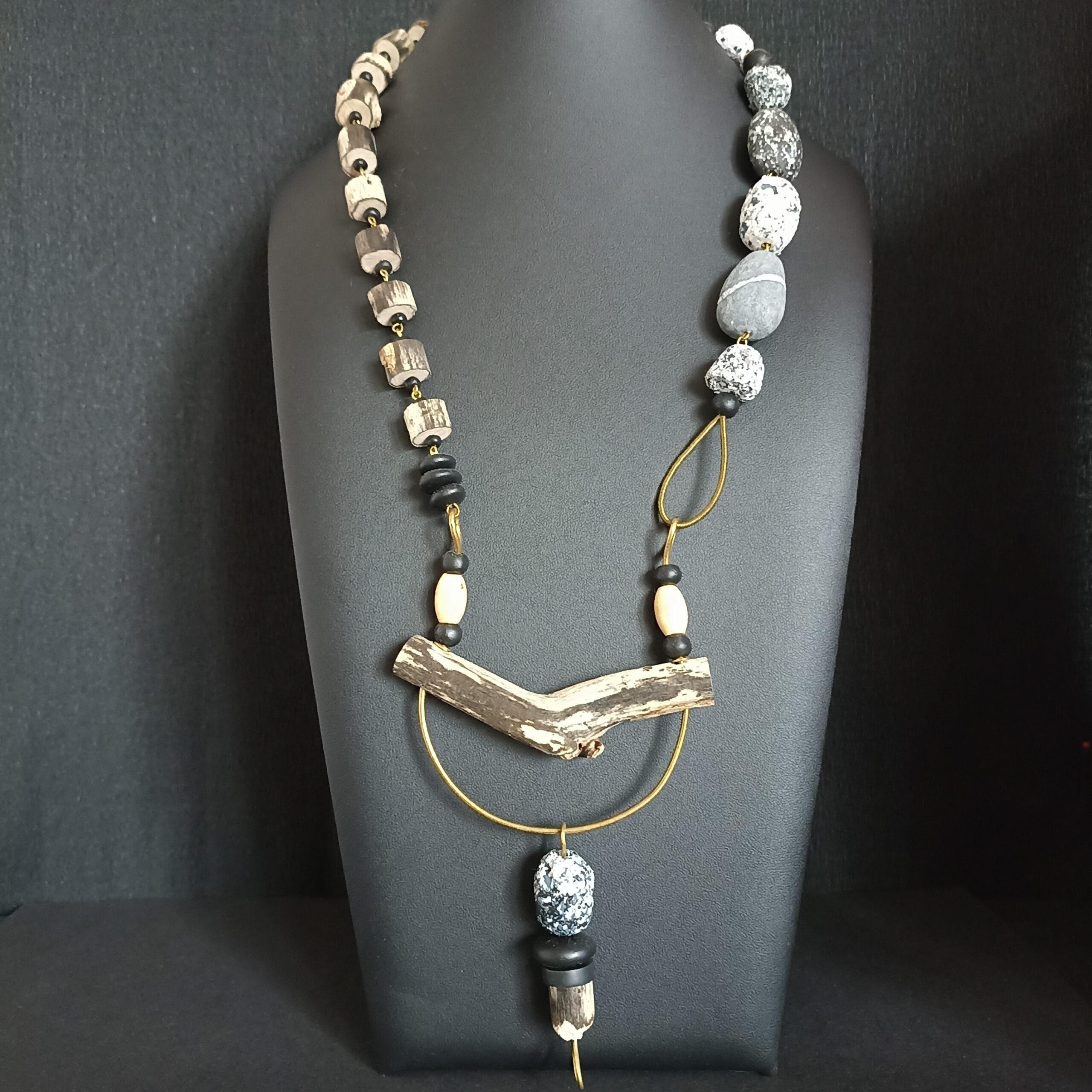 Collier long en bois flotté posé sur son support de présentation.