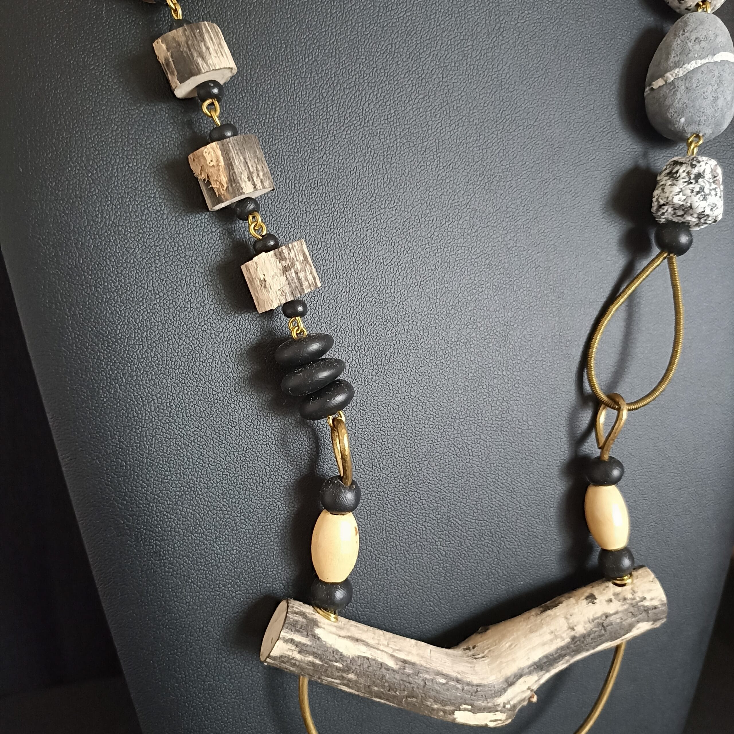 collier avec pendentif en bois flotté posé sur son support.