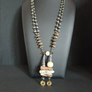 Collier Cairn en morceaux de bois flotté et petites perles, posé sur son présentoir.