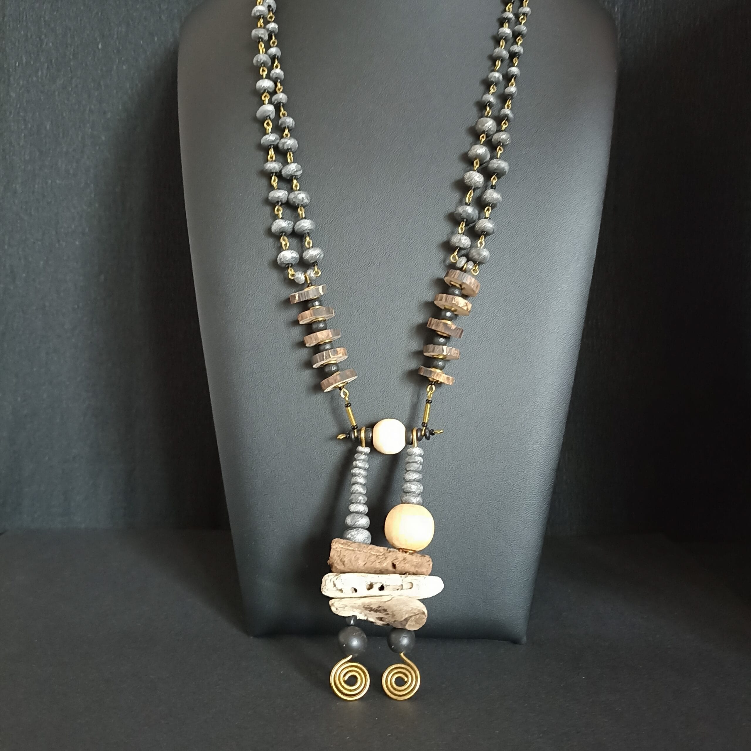 Collier Cairn en morceaux de bois flotté et petites perles, posé sur son présentoir.