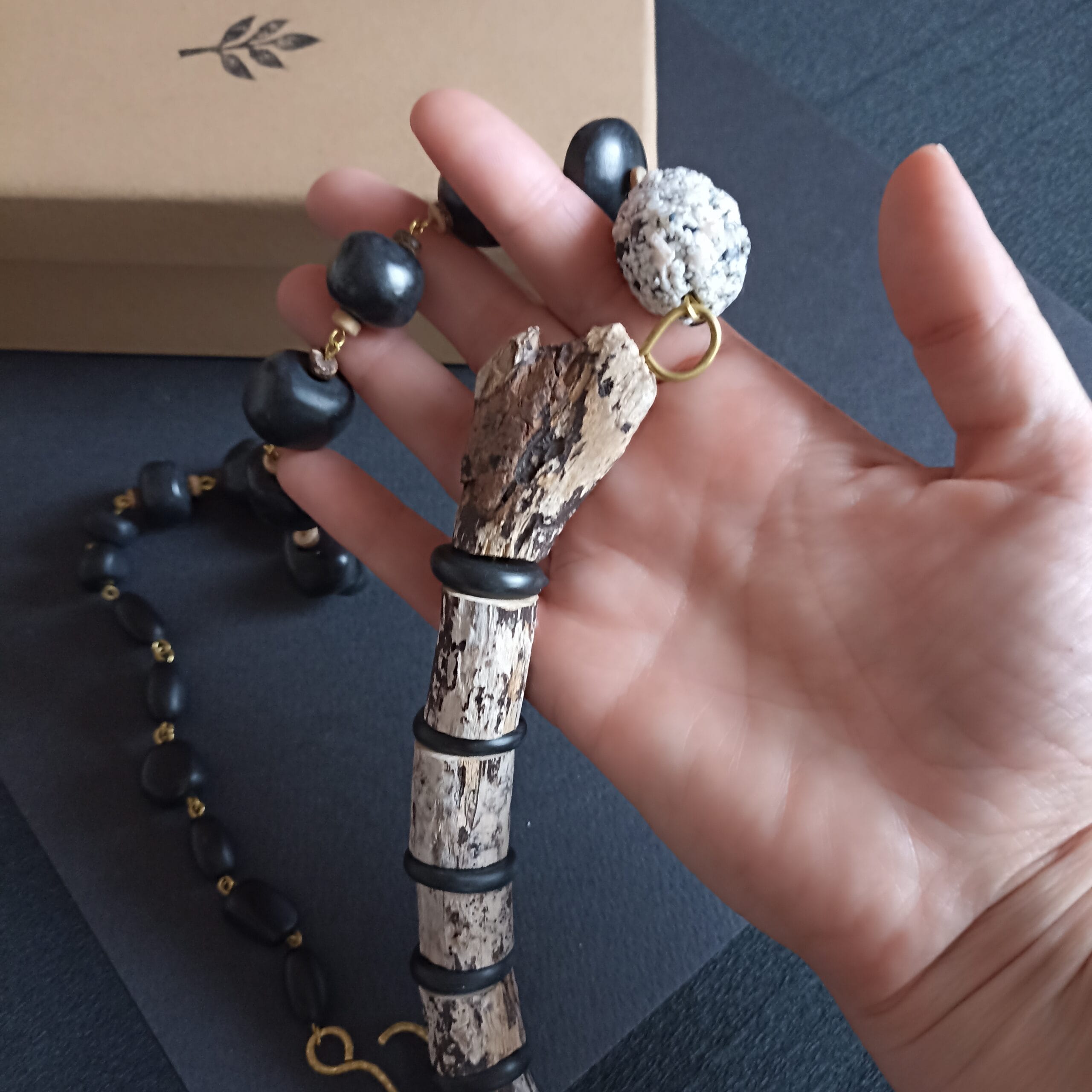 Collier Ecorce en bois flotté posé dans une main.