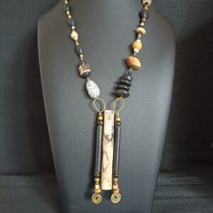Collier long avec pendentif en bois flotté et perles en bois, posé sur un buste de présentation.