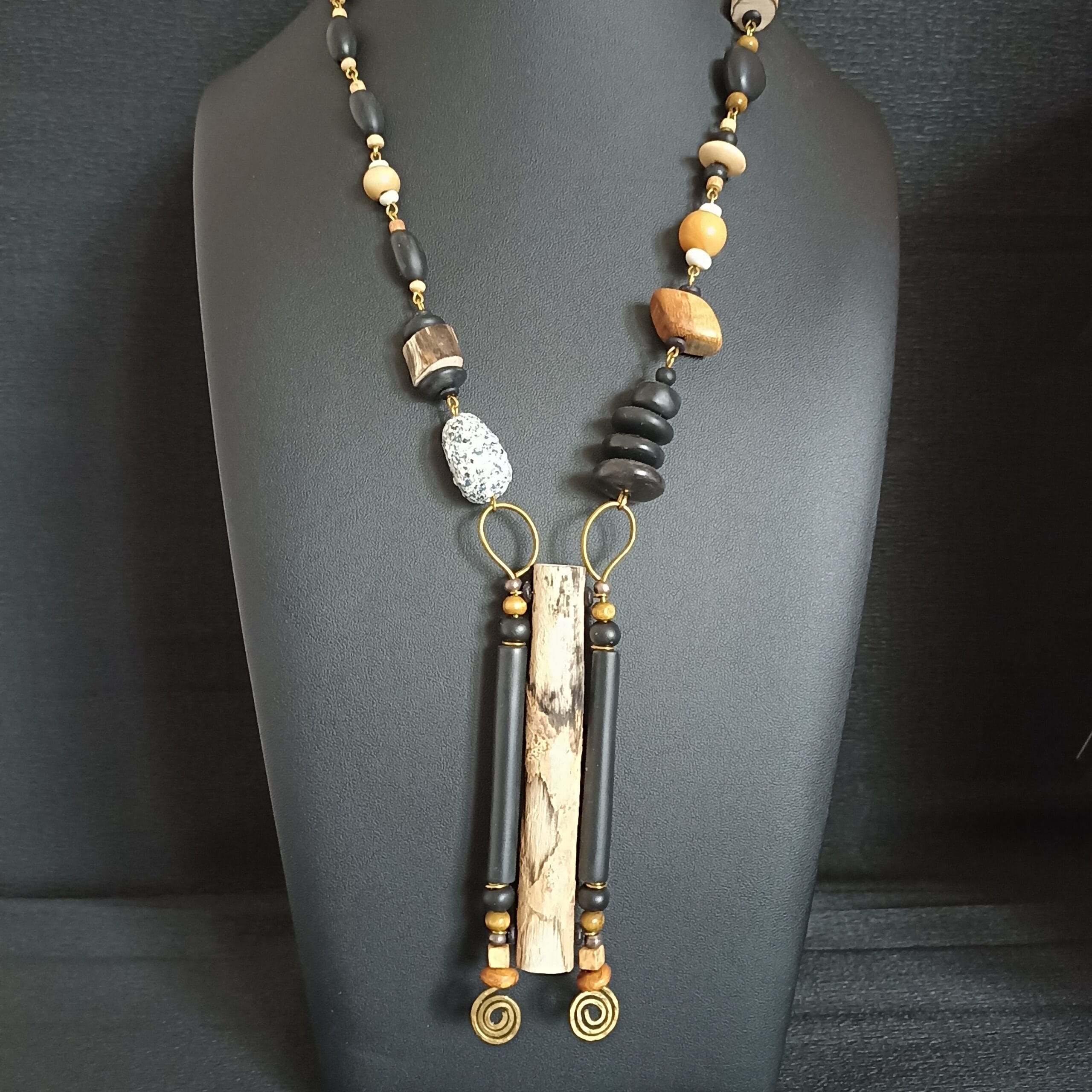 Collier long avec pendentif en bois flotté et perles en bois, posé sur un buste de présentation.