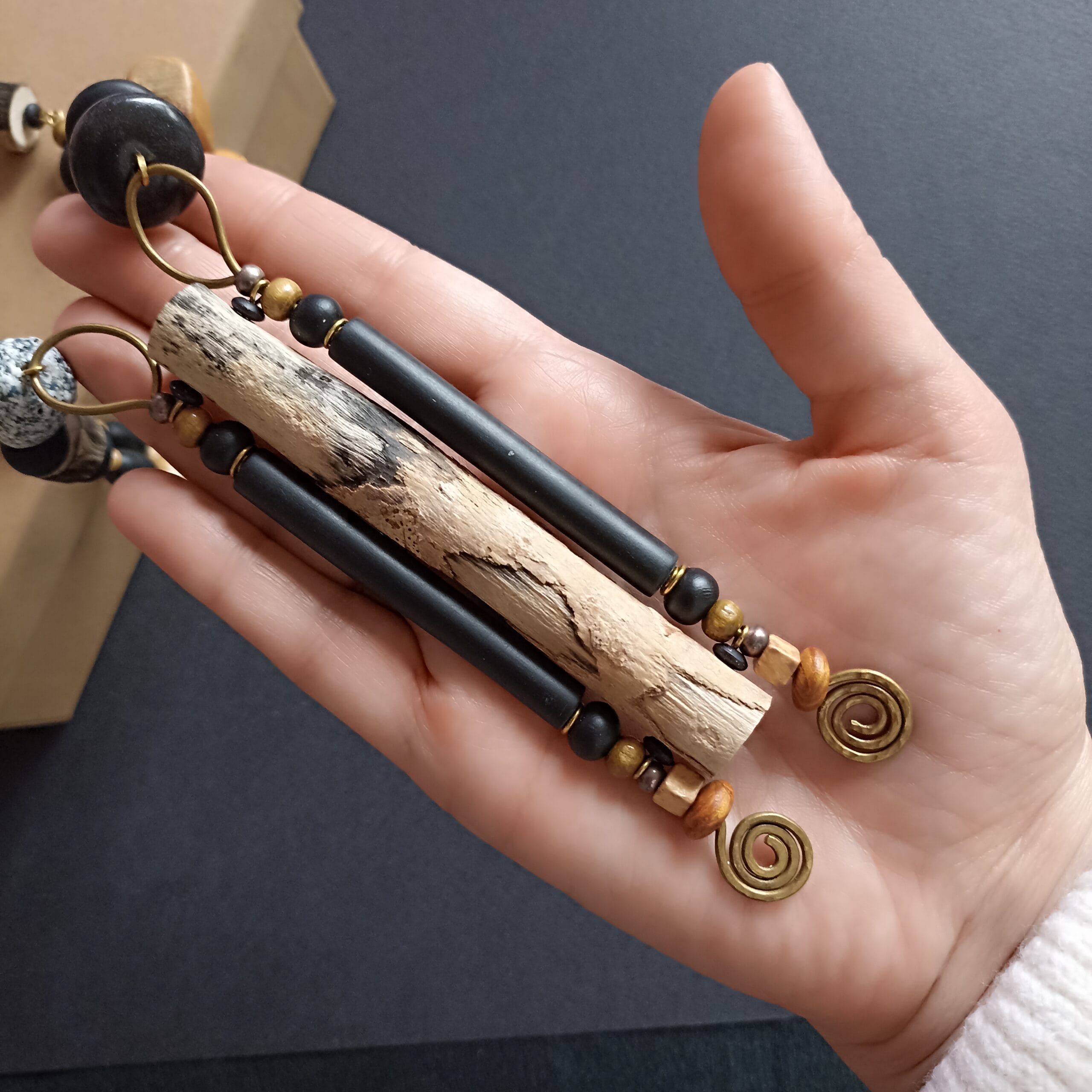 Pendentif du collier Rivage en bois flotté, posé dans ma main.