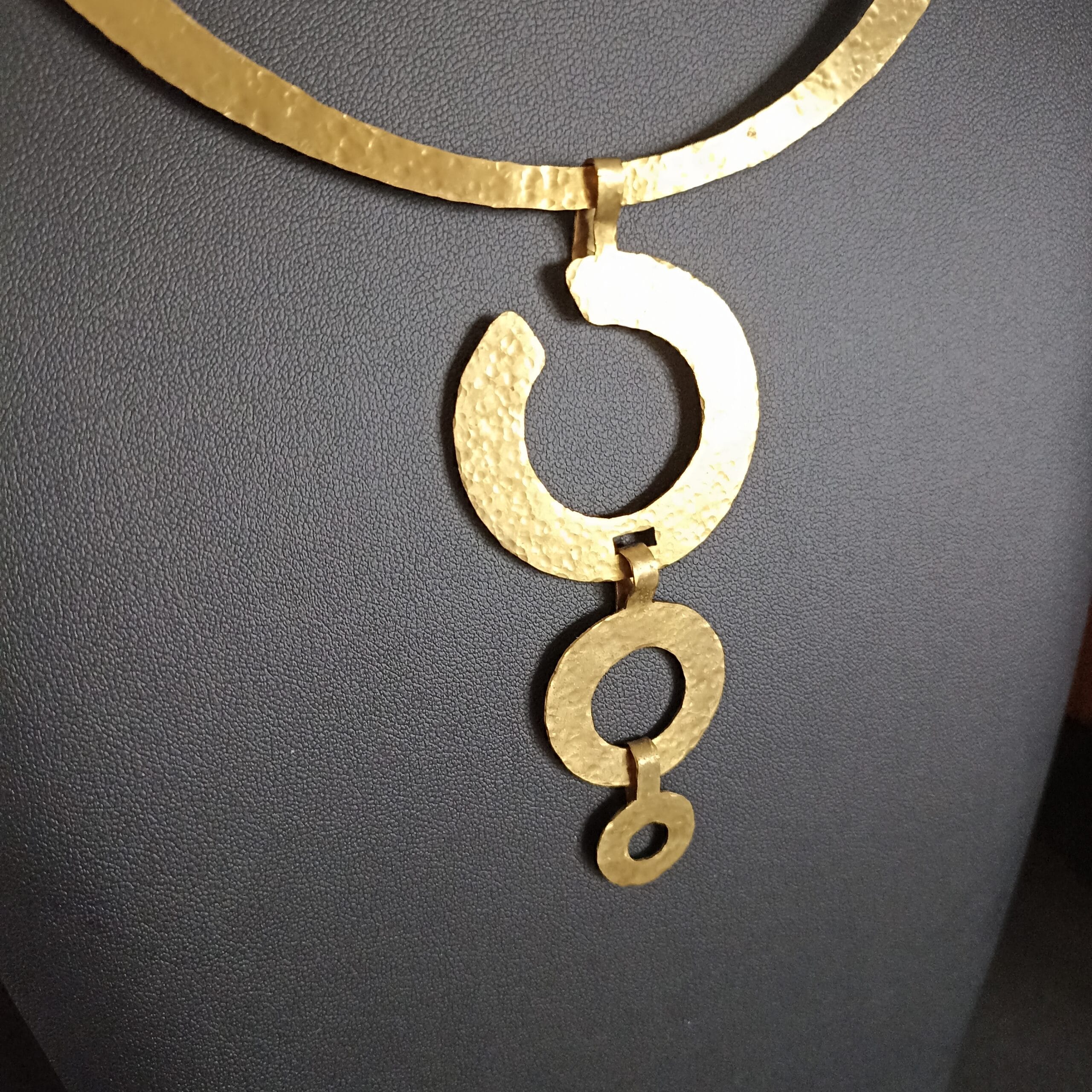 Gros plan sur le détail du pendentif en laiton martelé.