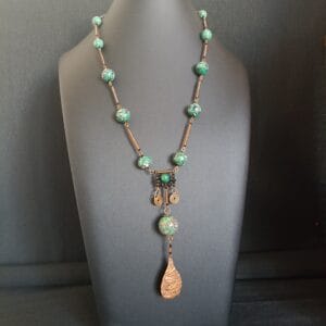 Collier long en perles vertes, rondes et éléments en cuivre martelé.