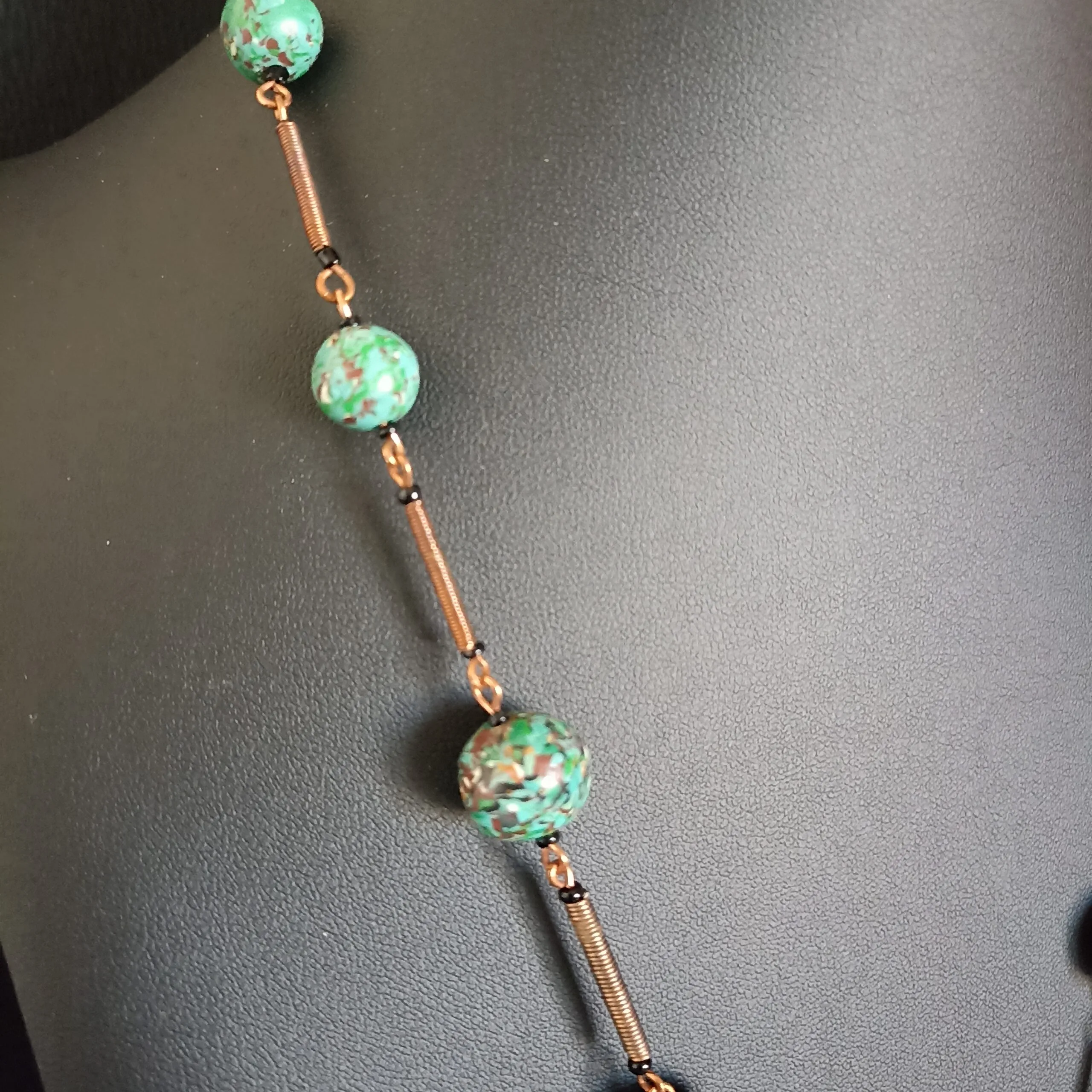 gros plan sur un collier en perles de polymère vertes et cuivre.