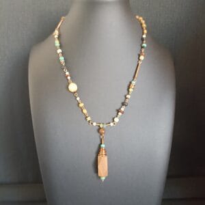 collier de style rustique en perles de bois et polymère, sur un buste de présentation.