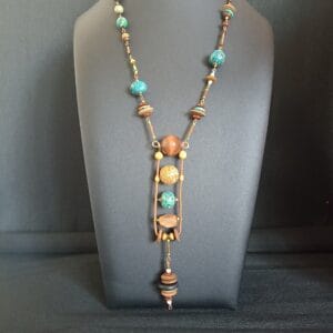 Collier en perles de bois et perles en polymère verte, posé sur un buste de présentation.